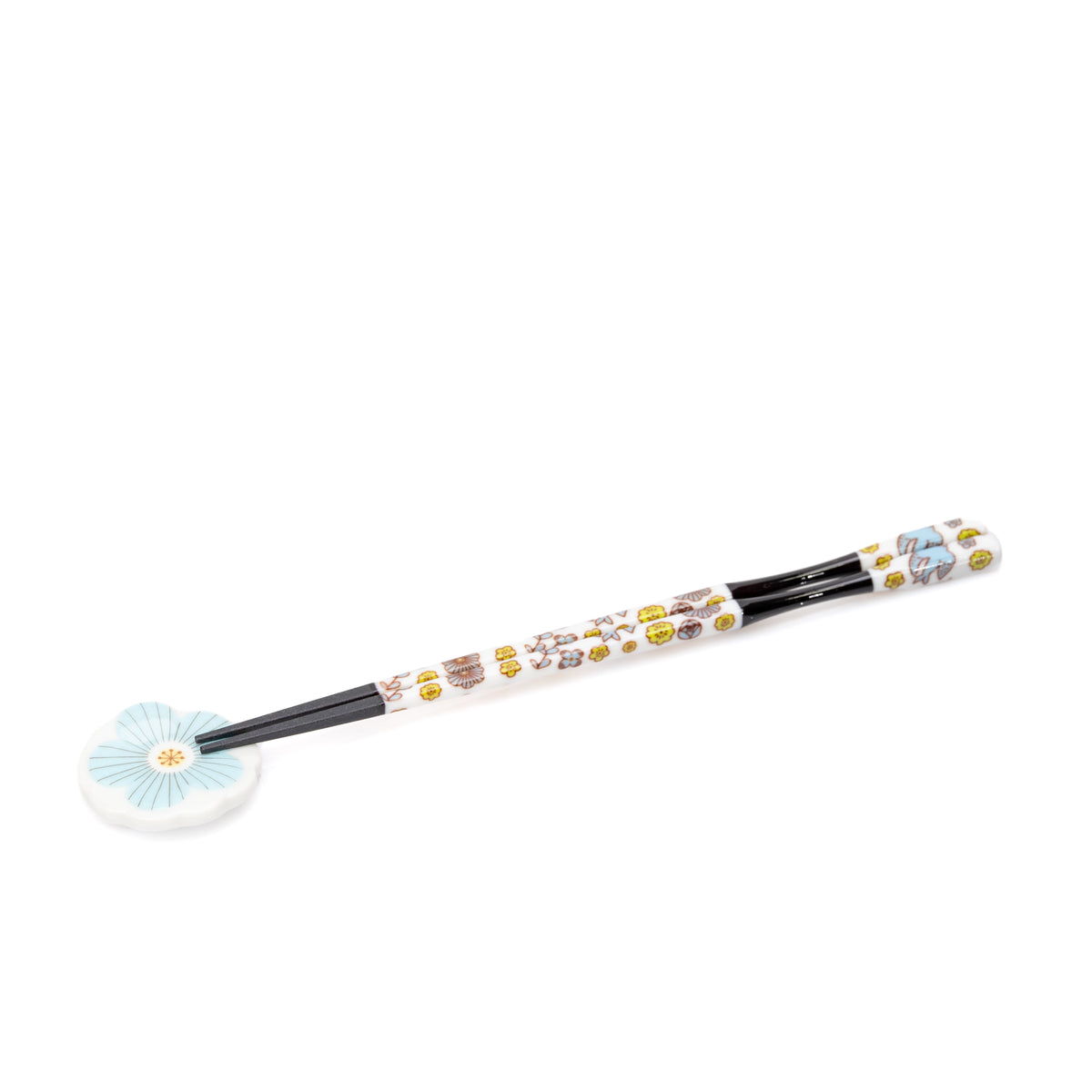 Black chopsticks with floral handles on a pale blue porcelain rest.