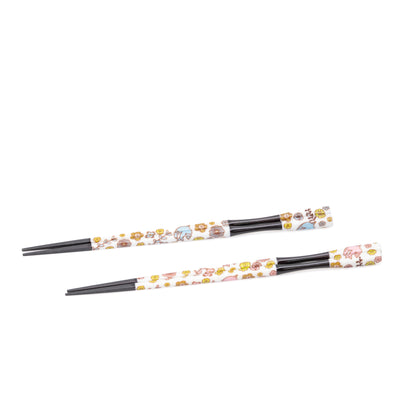 Two pairs of black chopsticks with floral handles arranged on white.