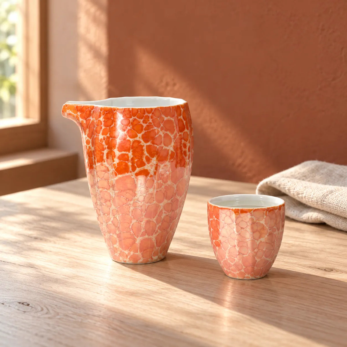 Red Jinpoh Champagne luster katakuchi pourer and matching small sake cup on a sunlit table