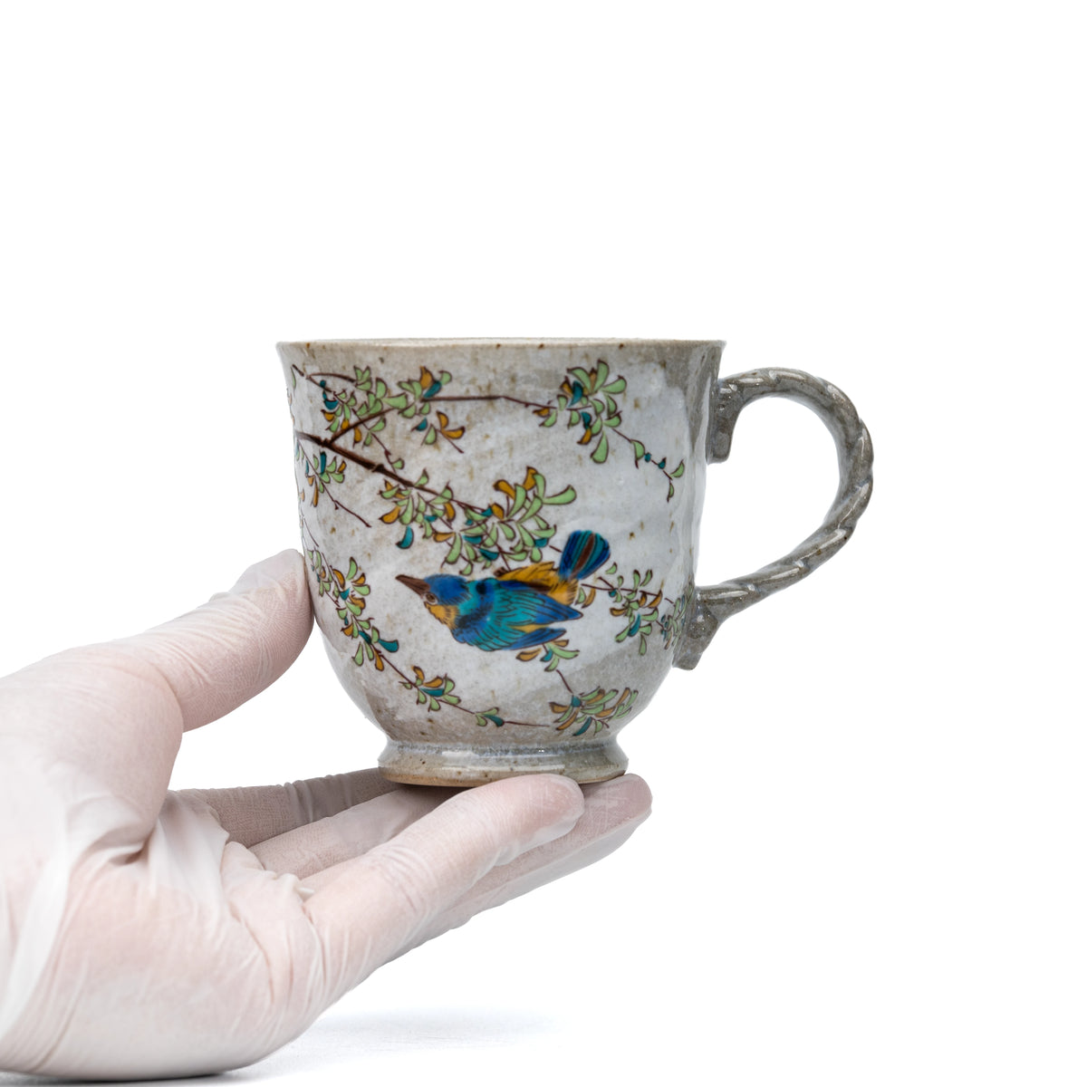 Kutani kingfisher mug held in a gloved hand to show scale.
