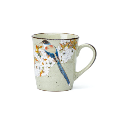 Pale green Kutani mug with a blue bird and white cherry blossoms on white.