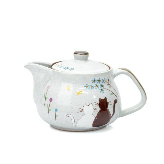 Pale gray Kutani teapot with two seated cats, small flowers and a rounded handle on white.