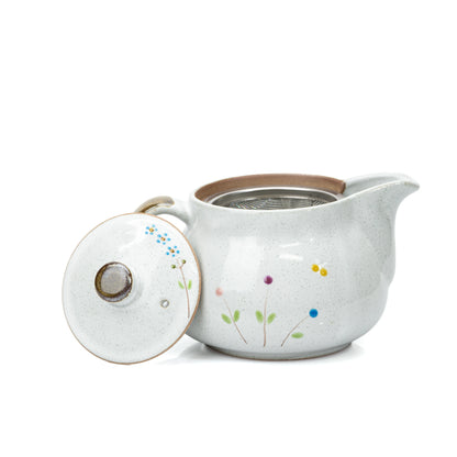 Open flower-painted side of the cat teapot with lid leaning beside it.