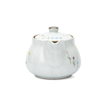 Back view of the pale glazed teapot and small flowers.