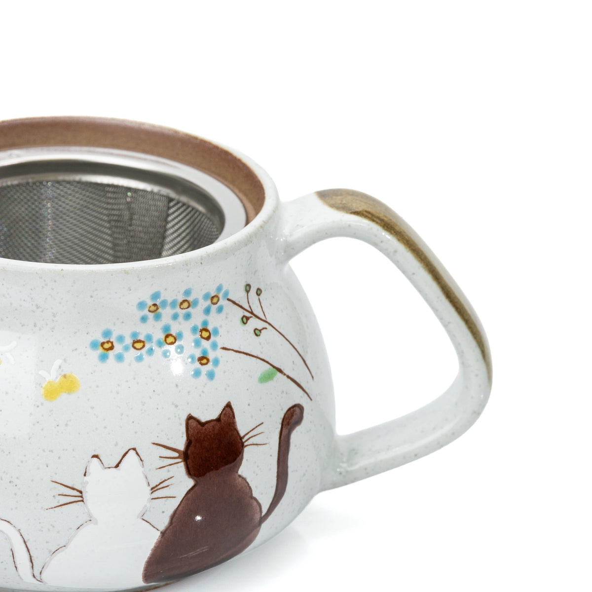 Close-up of two cats, painted flowers and the brown teapot handle.