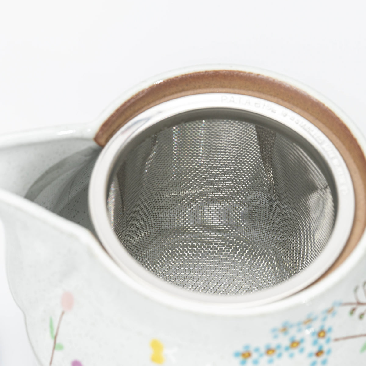 Top view of the removable metal strainer inside the teapot.