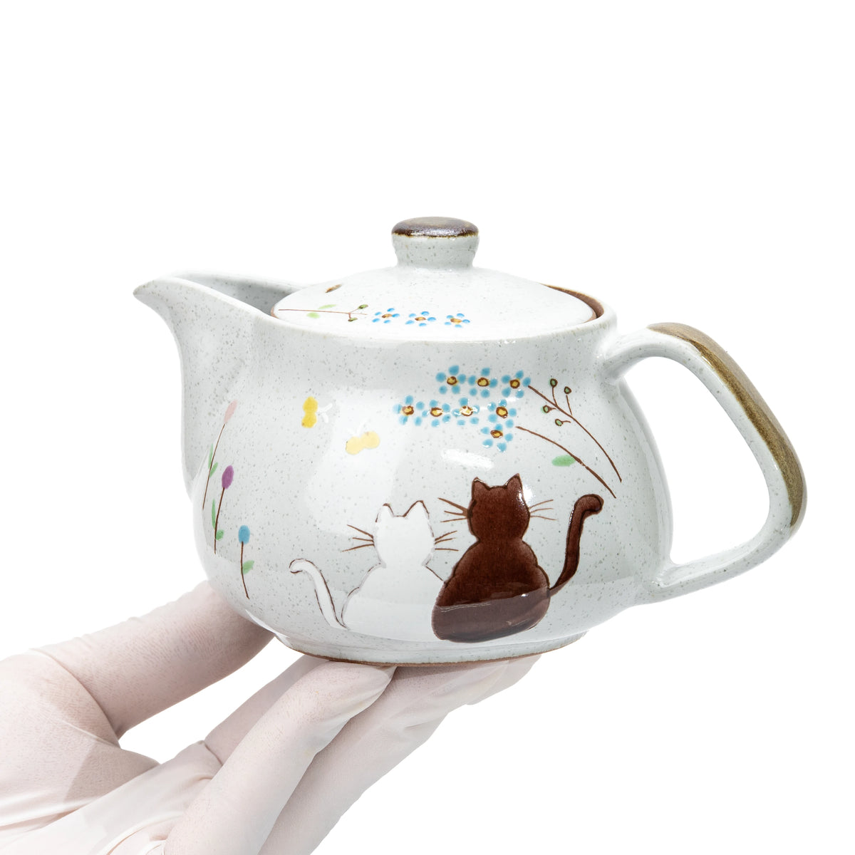 Kutani cat teapot held in a gloved hand.