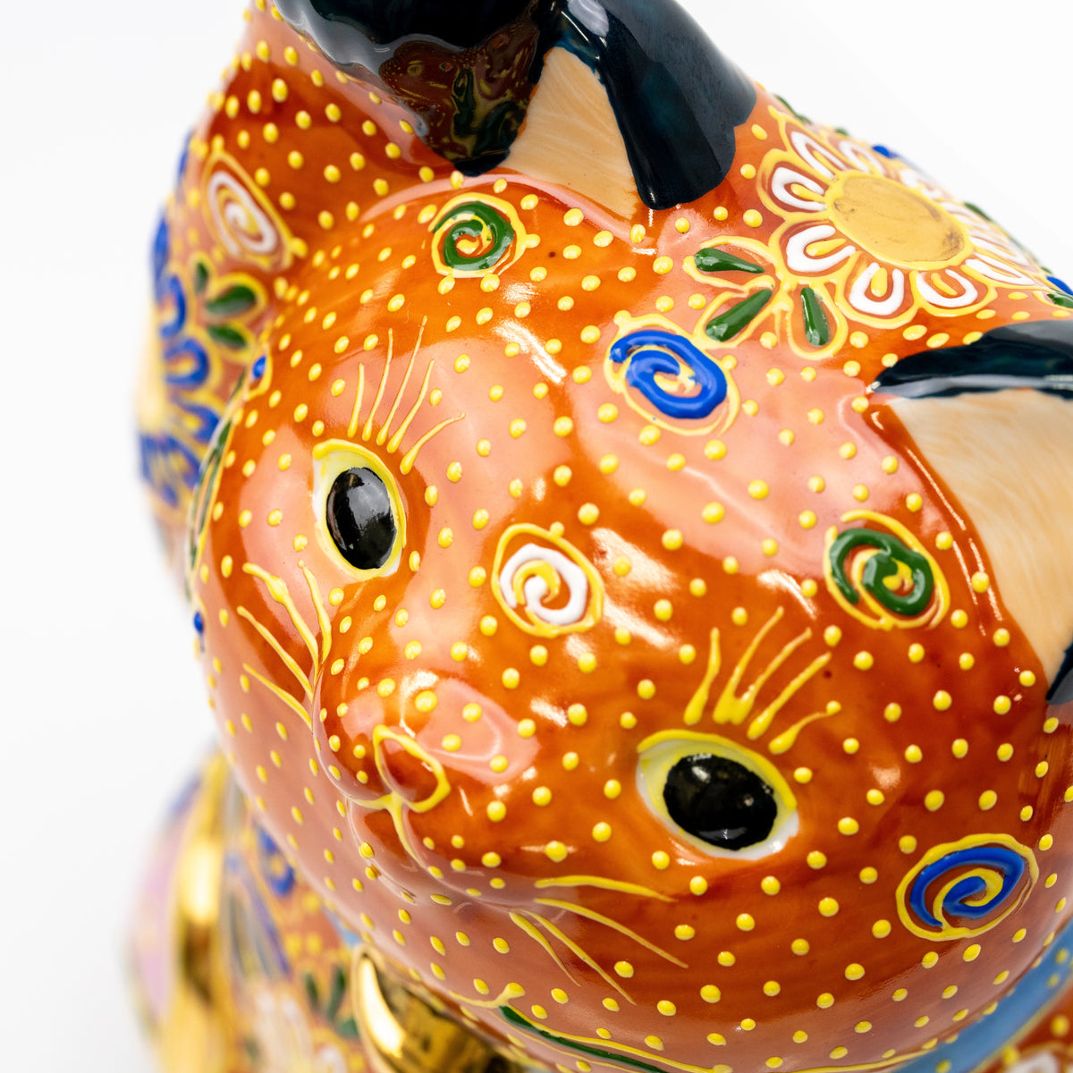 Close-up of the orange cat's face and gold dotted decoration.