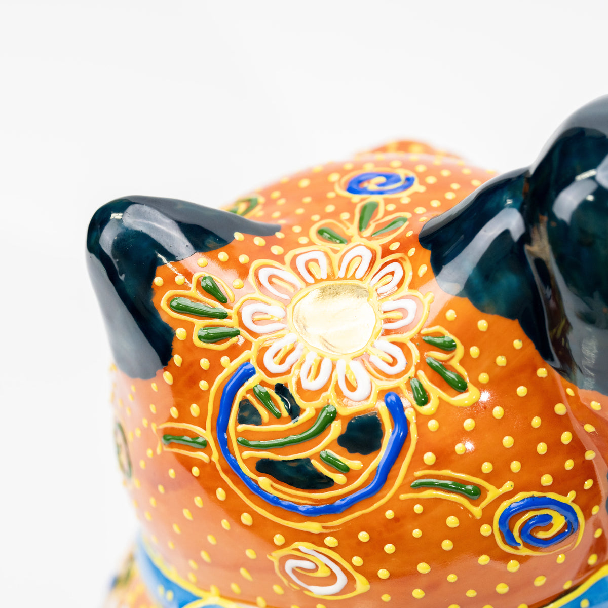 Top view of the cat's orange head with gold floral decoration.