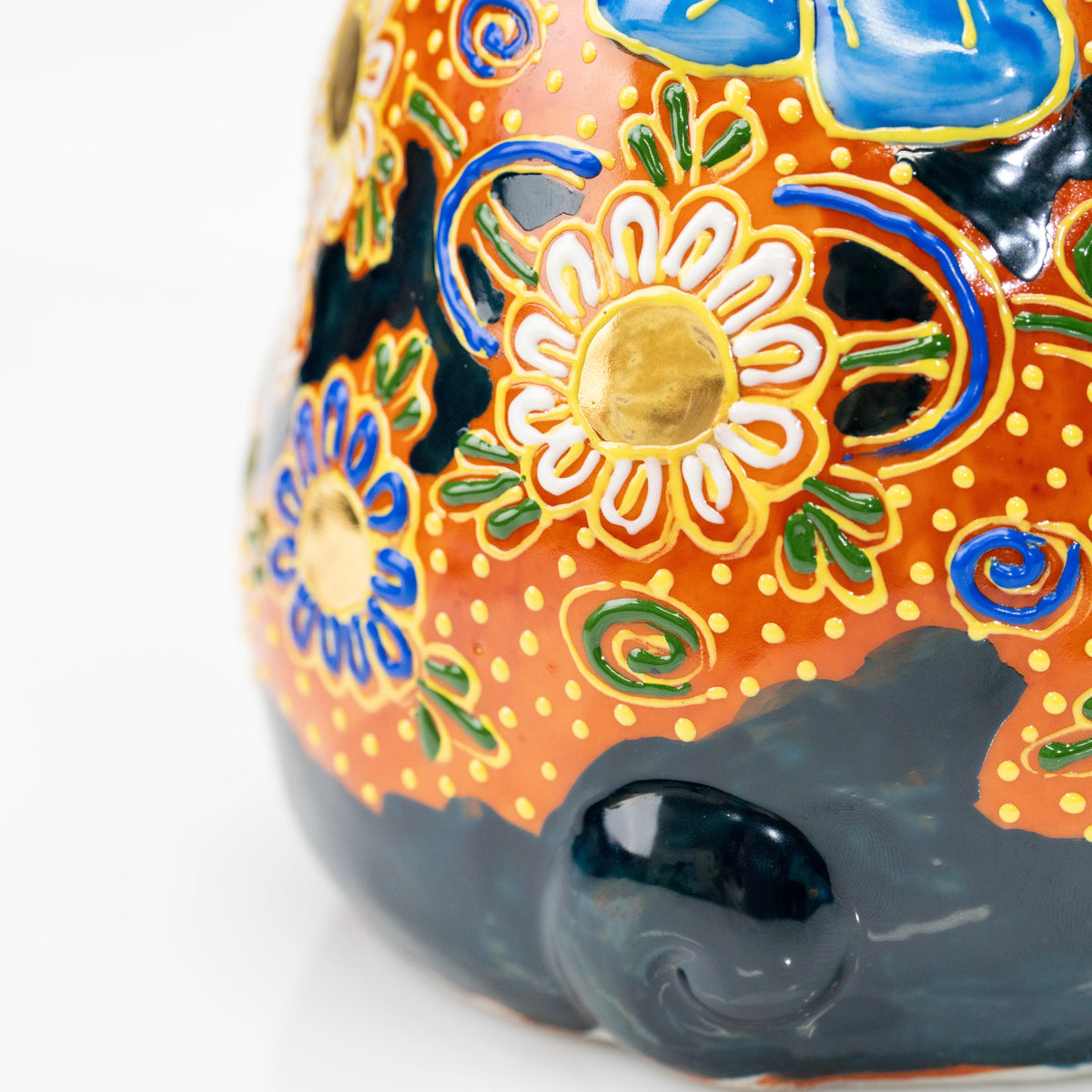 Close-up of raised gold floral details and black tail.