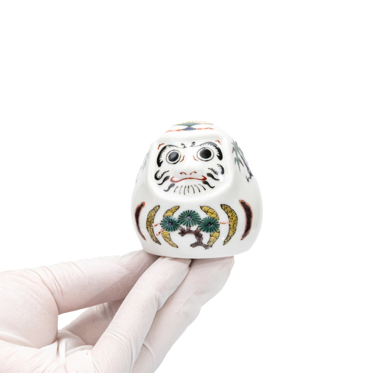Small white Kutani daruma held in a gloved hand.