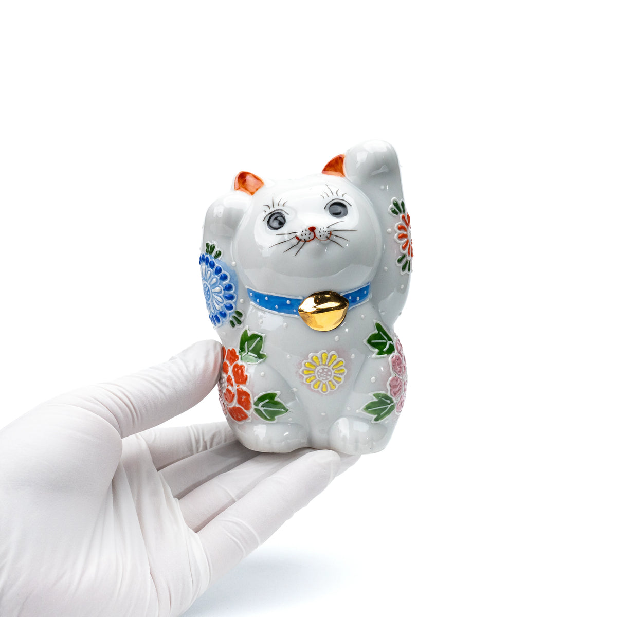 White floral lucky cat held in a gloved hand.