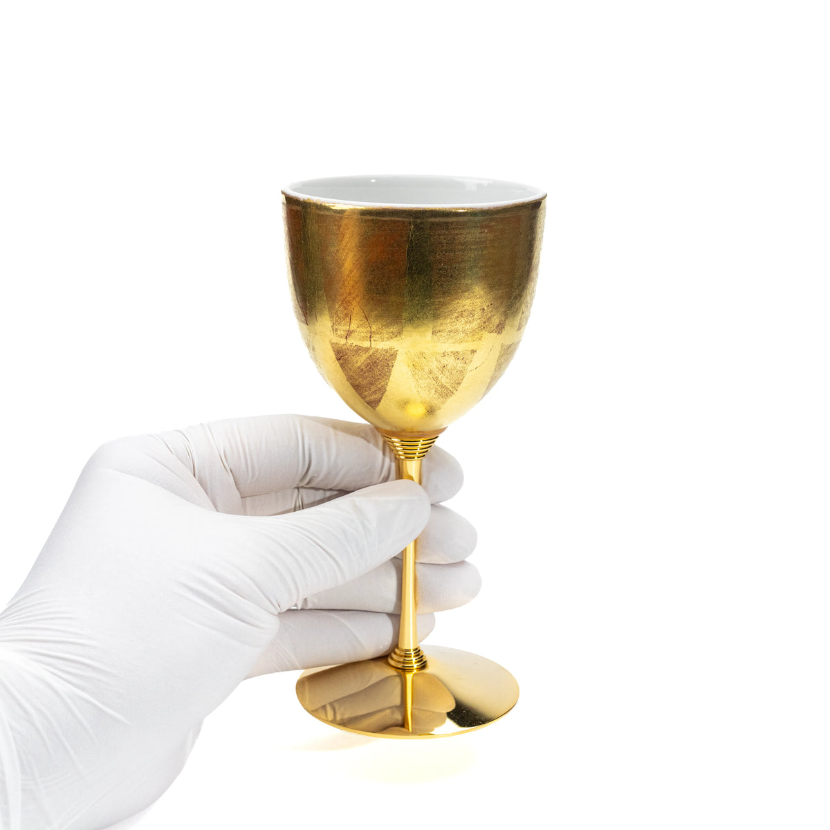 Gold-stemmed wine cup held in a gloved hand.