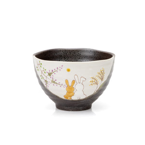 Dark glazed Kutani bowl with two seated rabbits and painted grasses on a cream panel.