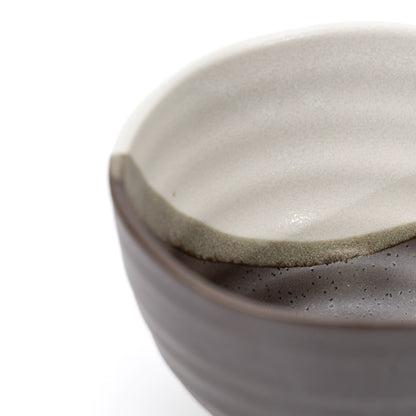 Close-up of the bowl's rim where cream decoration meets dark glaze.