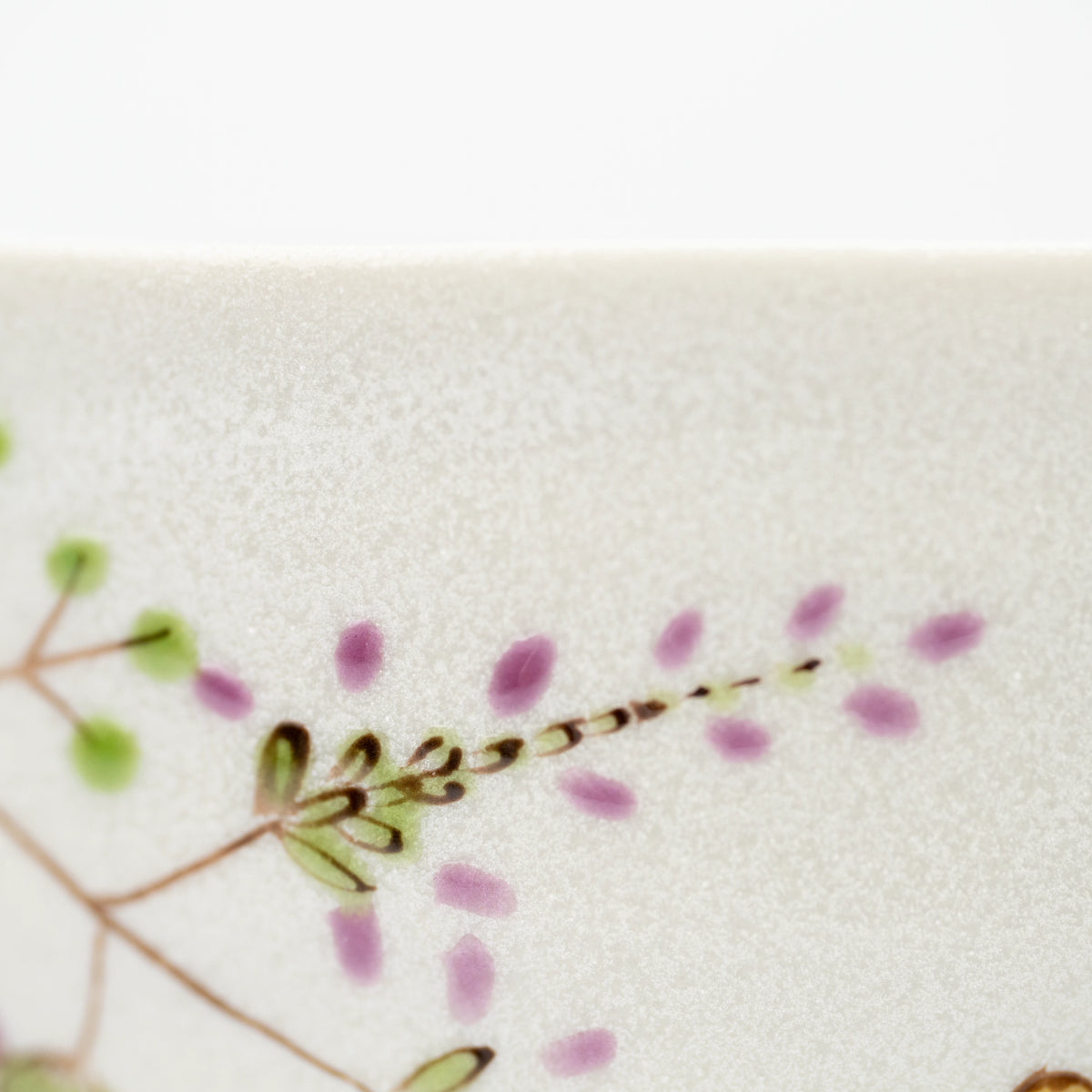 Close-up of purple flowers and green leaves painted on the rabbit bowl.