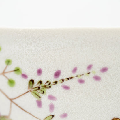 Close-up of purple flowers and green leaves painted on the rabbit bowl.