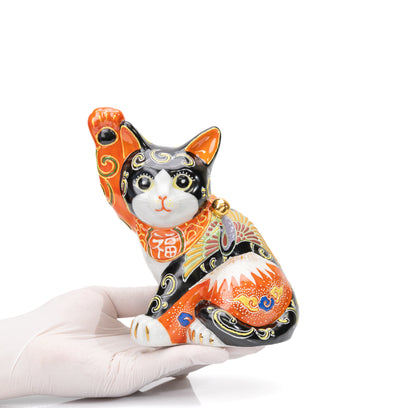 Mount Fuji and crane lucky cat held in a gloved hand.