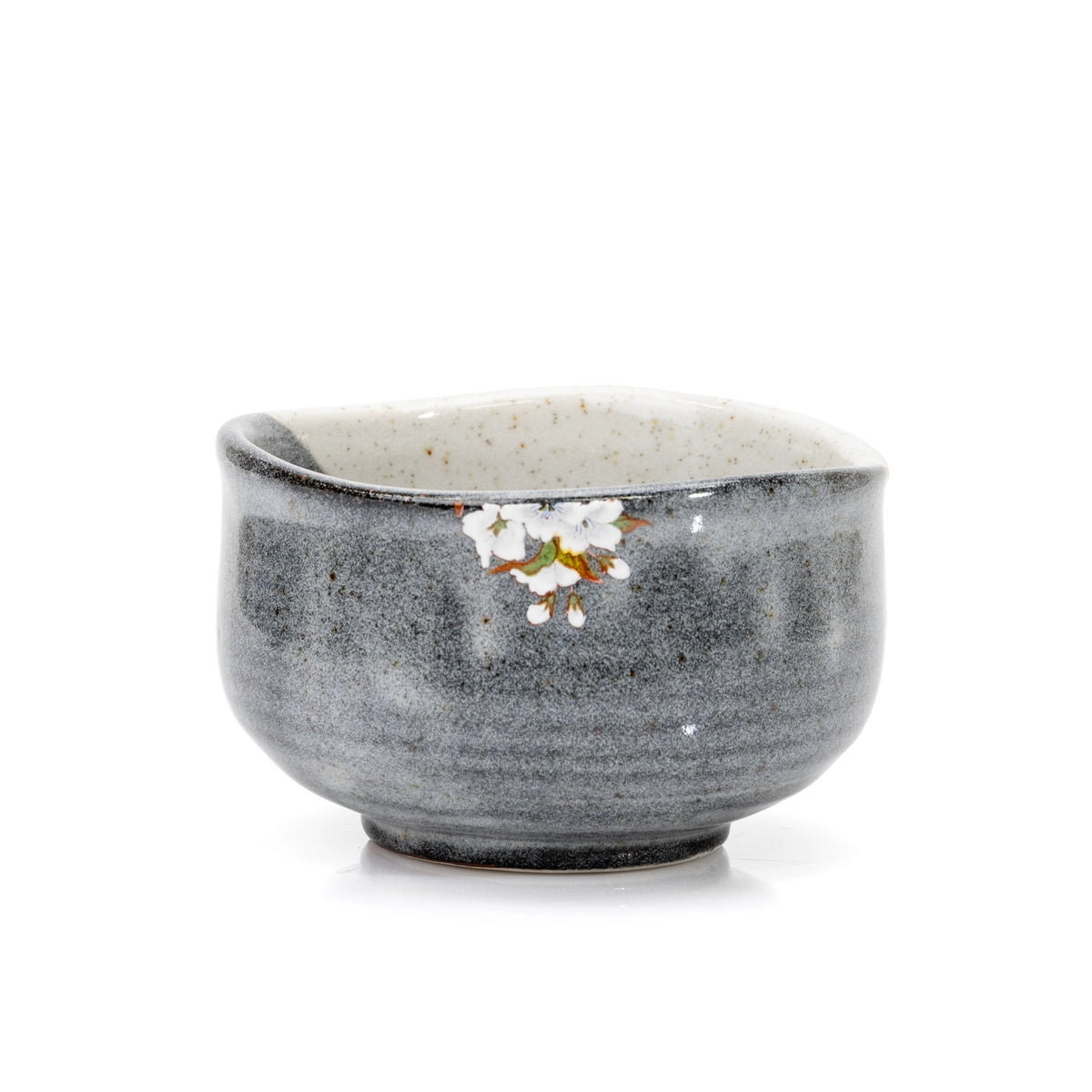 Back of the gray glazed matcha bowl with small white blossoms near the rim.