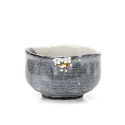 Back of the gray glazed matcha bowl with small white blossoms near the rim.