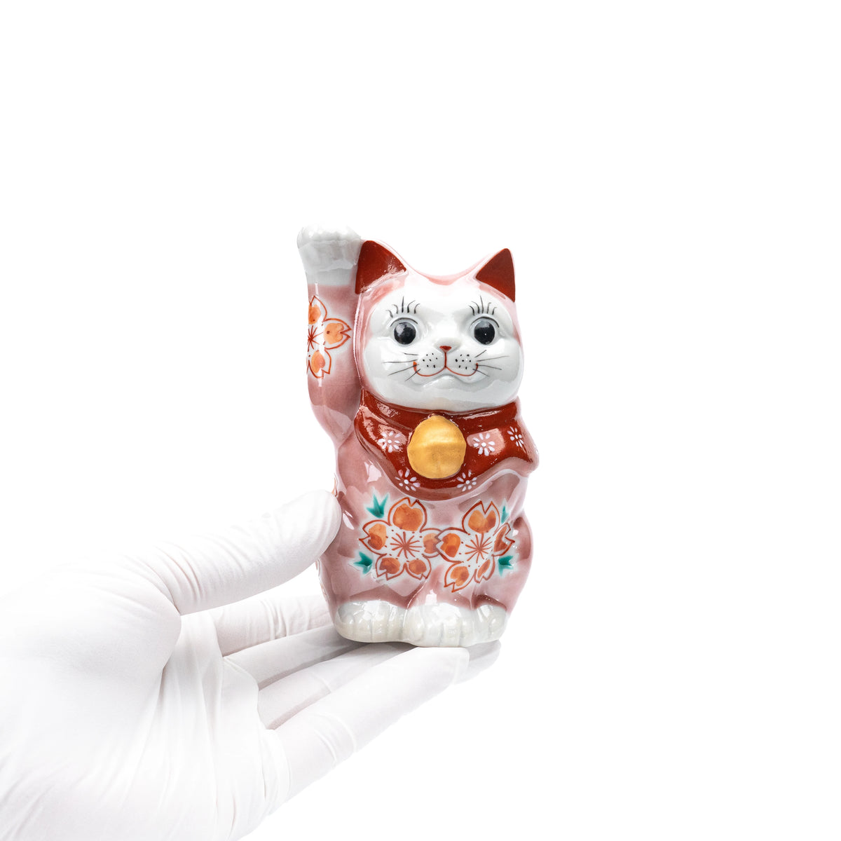 Pink cherry blossom lucky cat held in a gloved hand.