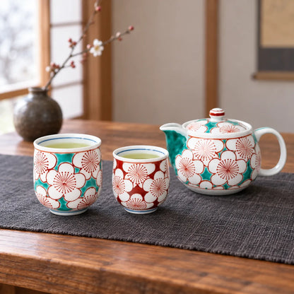 Kutani plum blossom teapot with a larger turquoise cup and smaller red cup on a low table