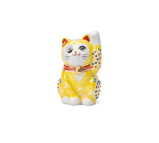 Small yellow Kutani lucky cat with a raised paw, colorful floral dots and a gold bell on white.