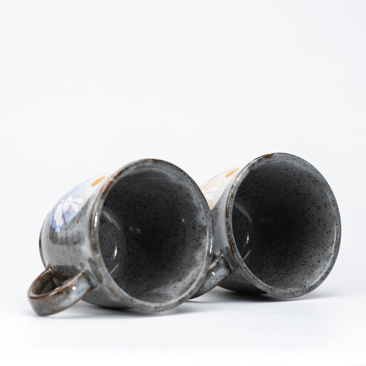 Dark speckled interiors of the two mugs.
