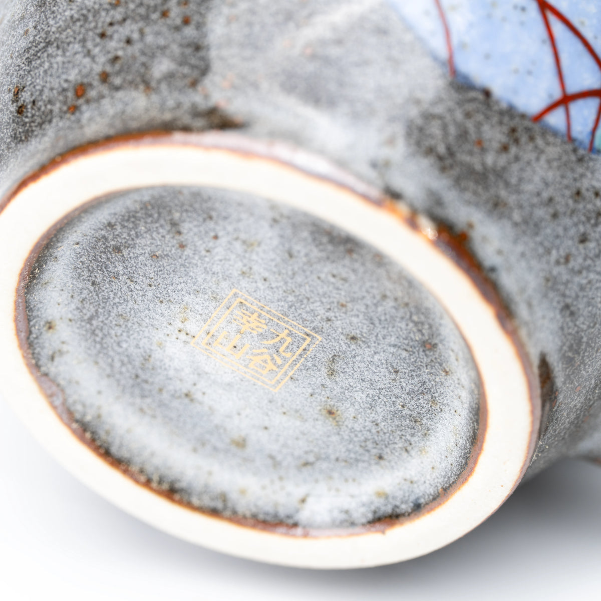 Gold-colored maker's mark on the underside of a rabbit mug.