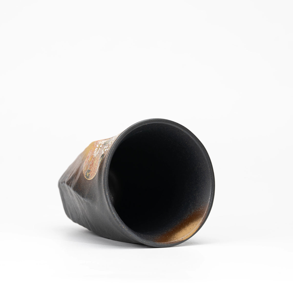 Black Kutani cup tilted to show its dark interior.