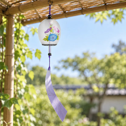 Frosted glass morning glory wind chime with purple patterned paper strip hanging under a bamboo trellis