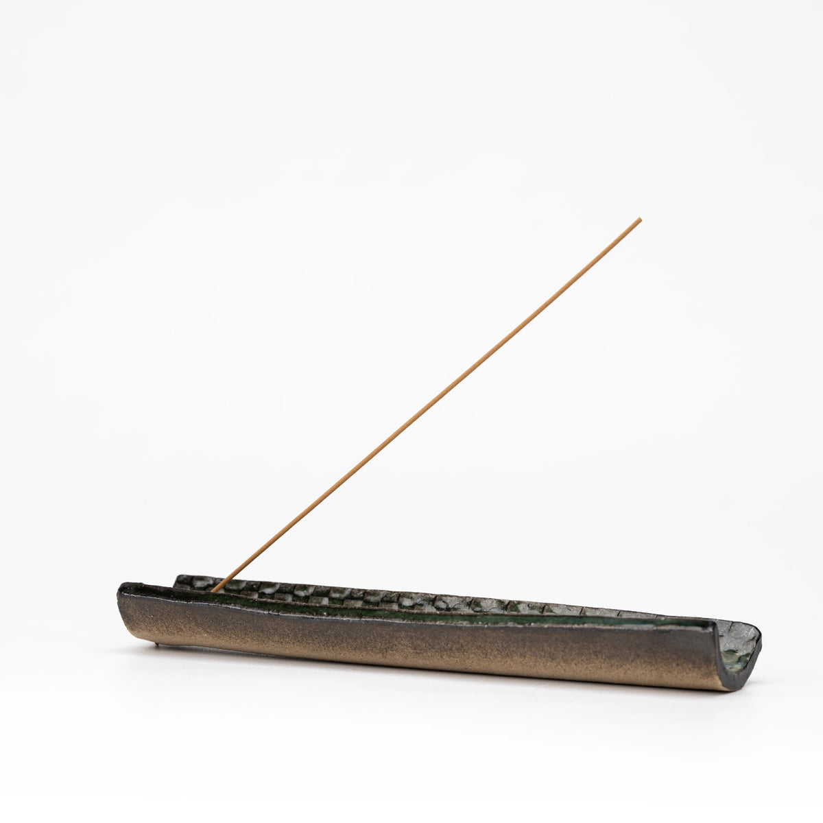 Side view of the long dark incense tray and incense stick.