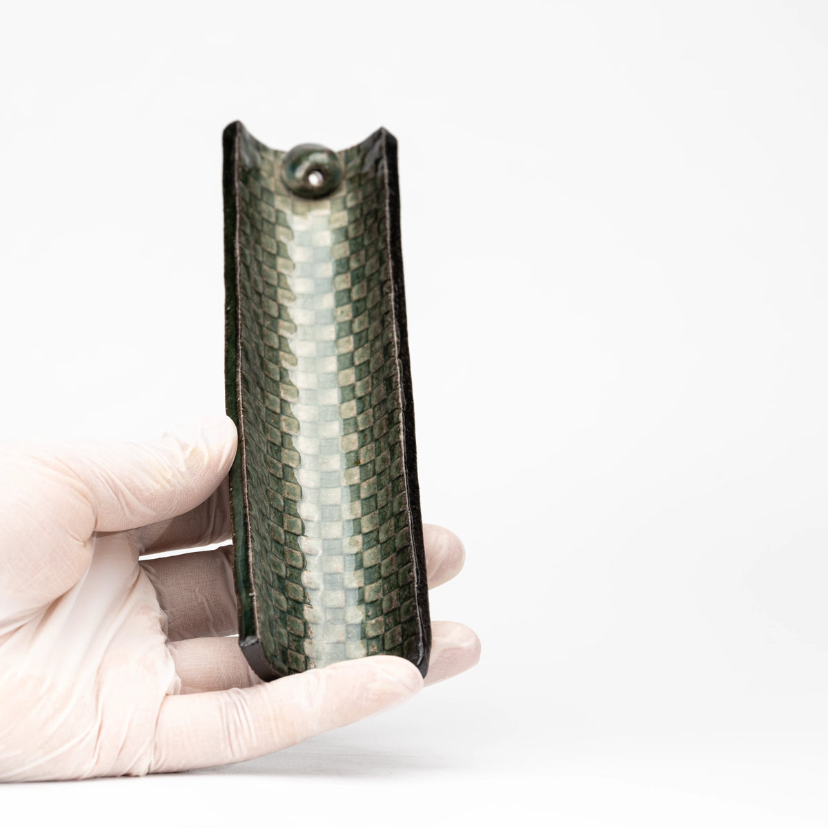 Mosaic incense holder held vertically in a gloved hand to show scale.