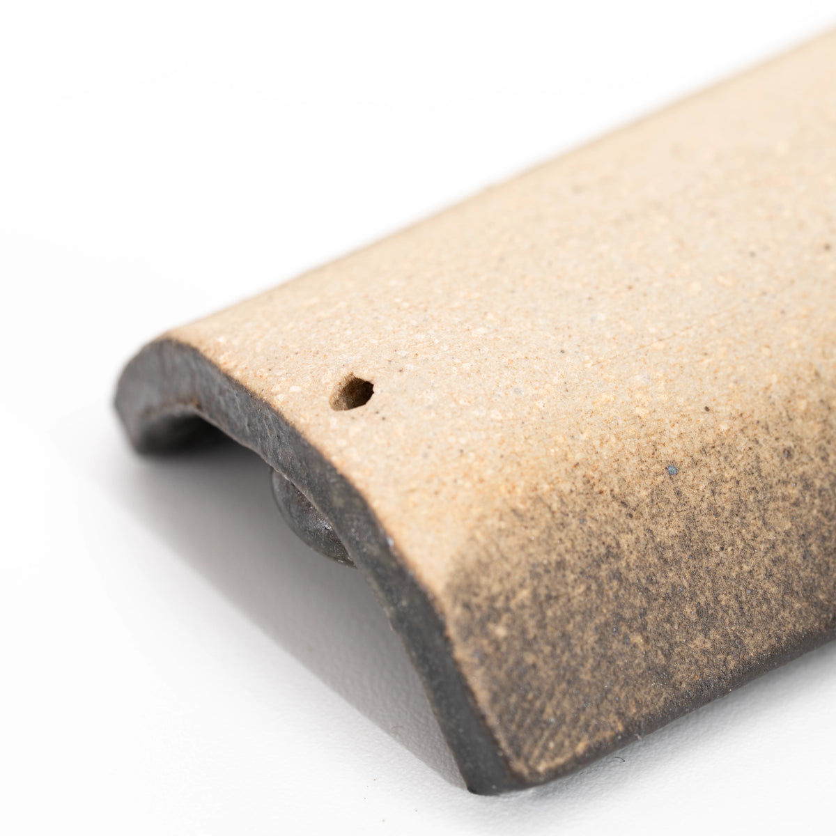 Close-up of a hole and the unglazed underside of the incense tray.
