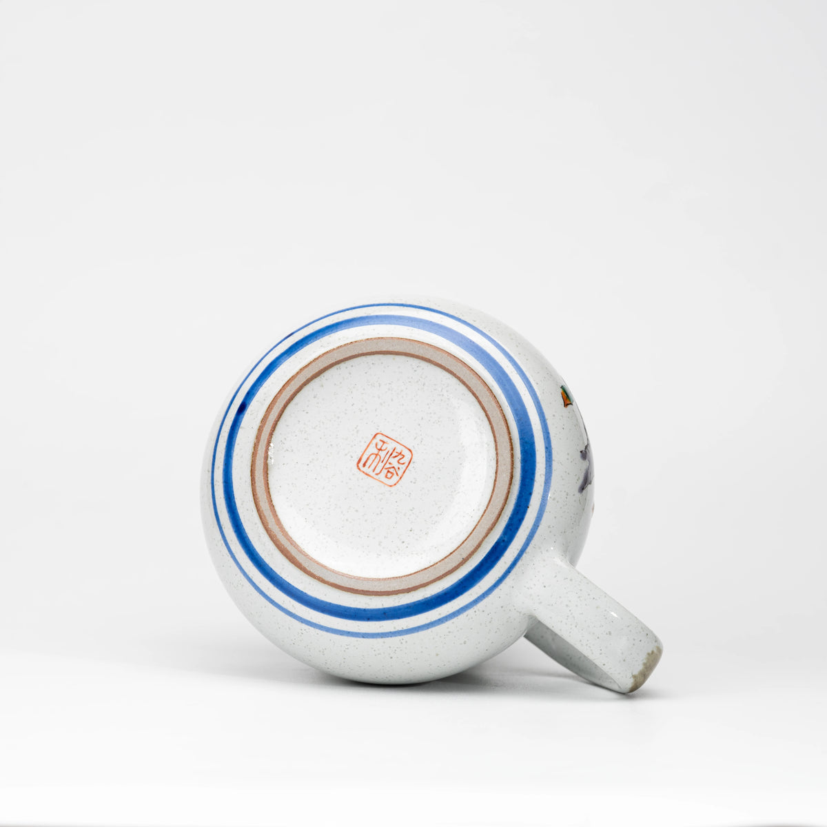Underside of the Kutani owl teapot with a red maker's mark and blue rings.