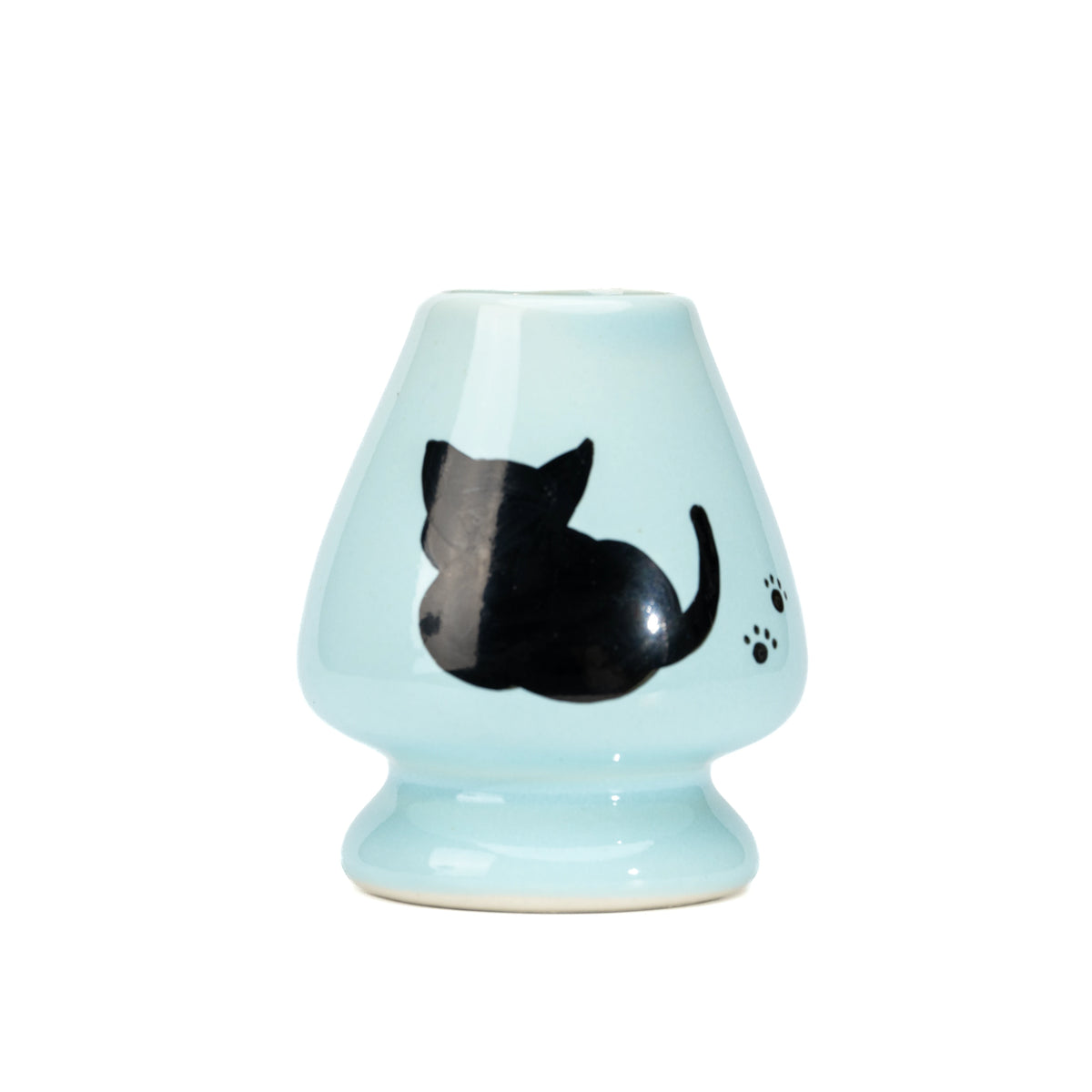 Pale blue ceramic matcha whisk holder with a black cat and paw prints on white.