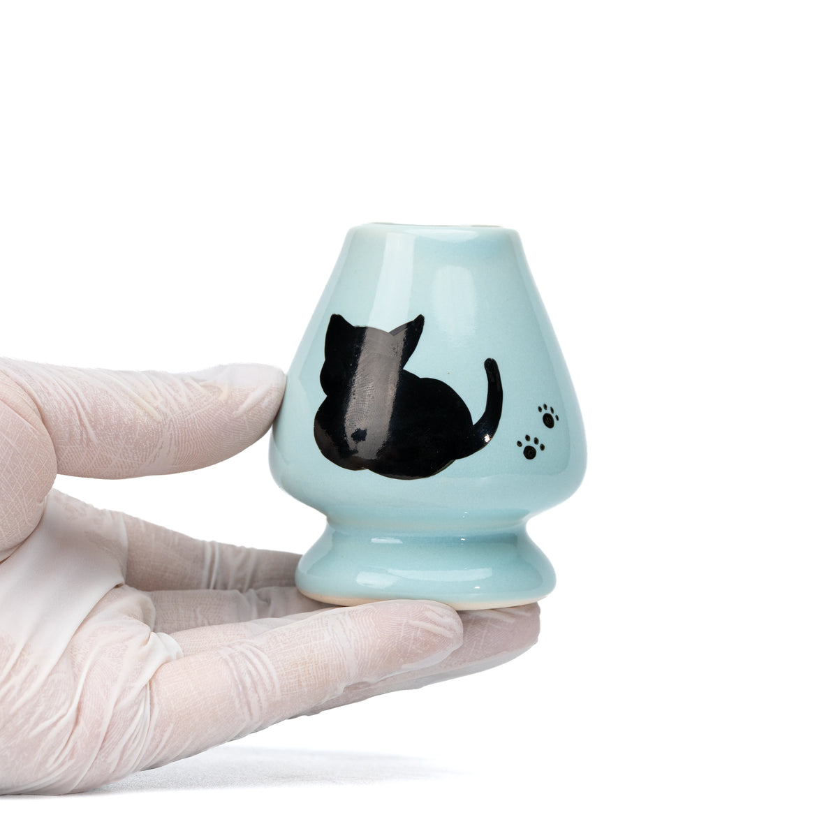 Pale blue cat whisk holder held in a gloved hand.