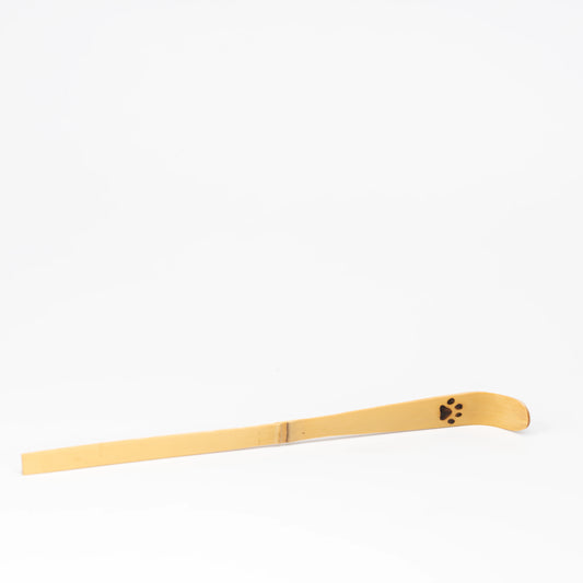 Bamboo matcha scoop with a paw print near its curved tip on a white background.