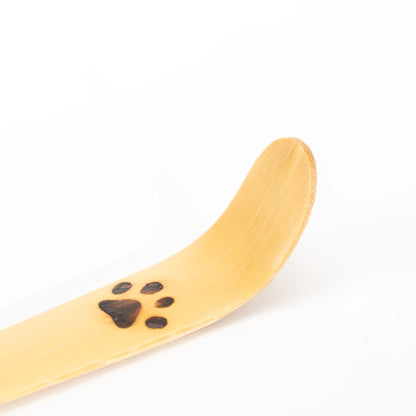 Close-up of the dark paw print on the curved bamboo scoop.