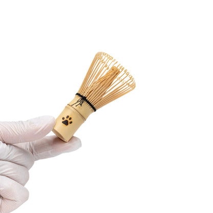 Mini bamboo matcha whisk held in a gloved hand.