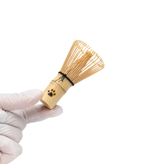 Mini bamboo matcha whisk held in a gloved hand.