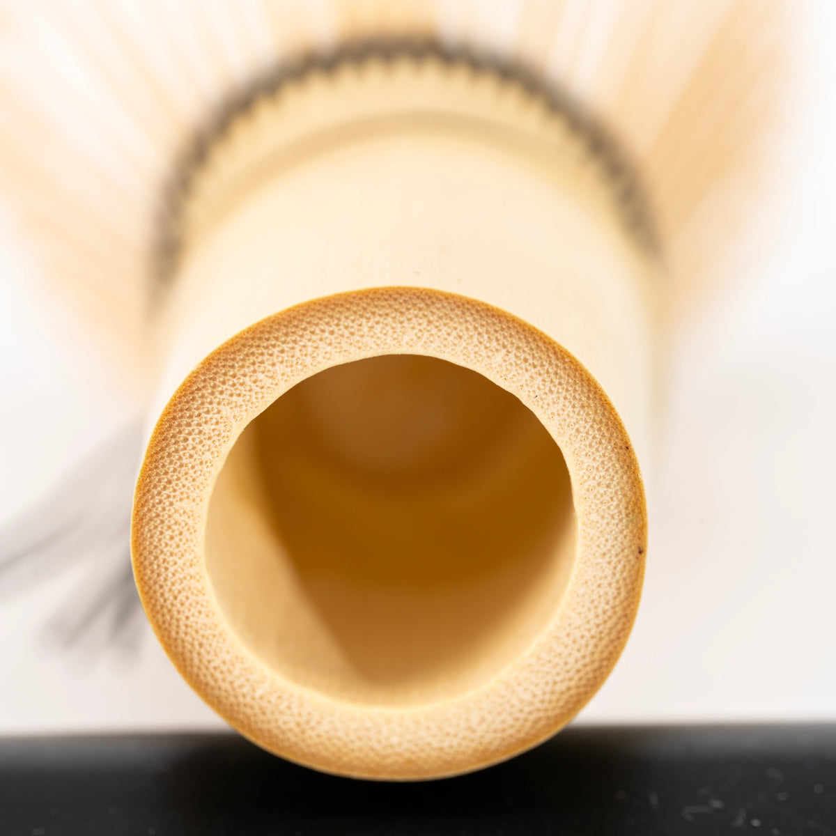 Circular hollow at the base of the bamboo whisk handle.