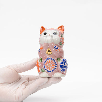 Pink floral praying cat held in a gloved hand.