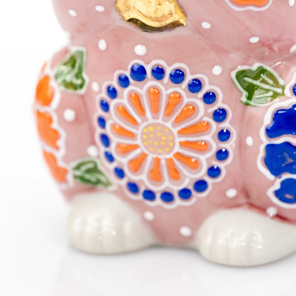 Close-up of the orange flower and white paws on the pink cat.