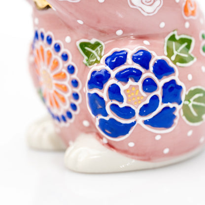Raised blue flower decoration on the pink ceramic cat.