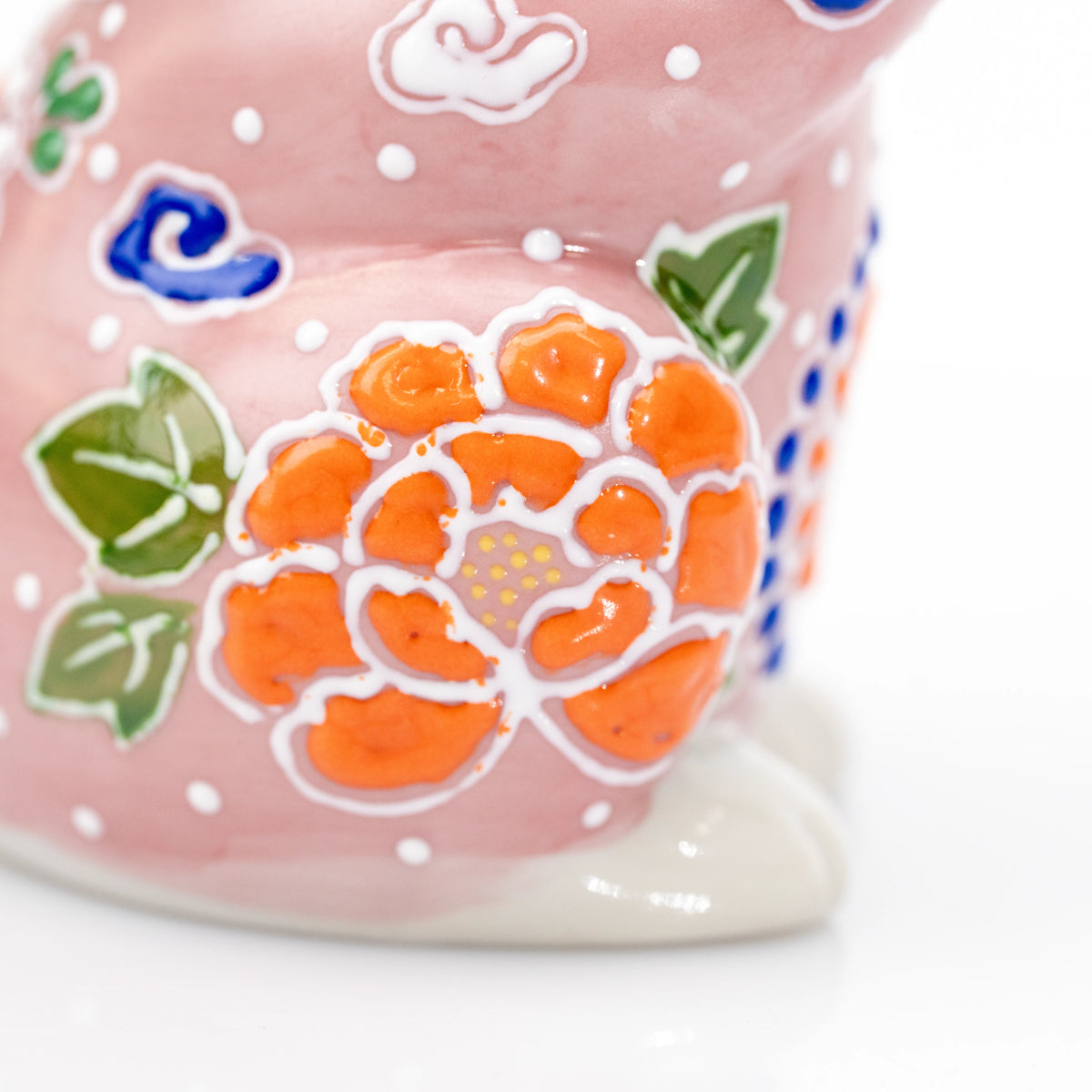 Raised orange and green floral details on the pink cat.