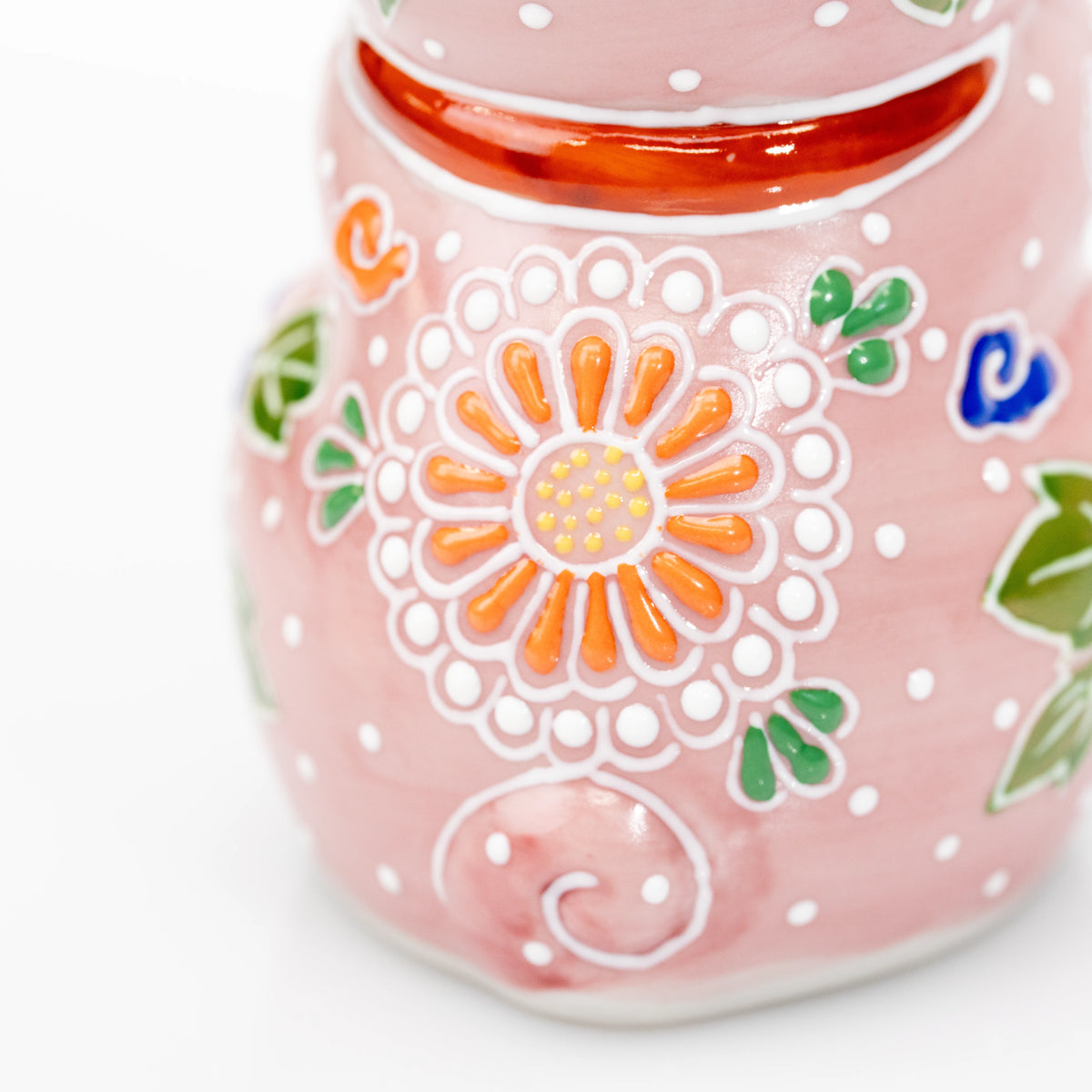 Red collar and orange flower on the back of the pink cat.