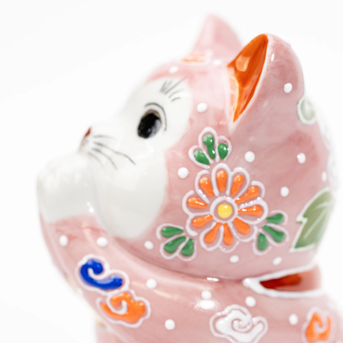 Profile of the cat's white face, orange ear and floral decoration.