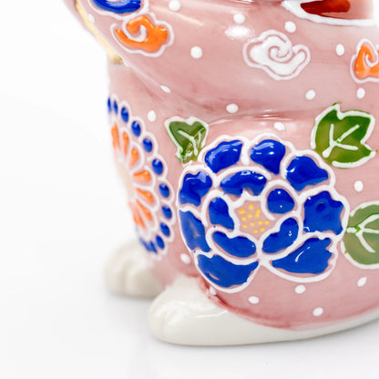 Close-up of blue and orange floral decoration near the cat's feet.