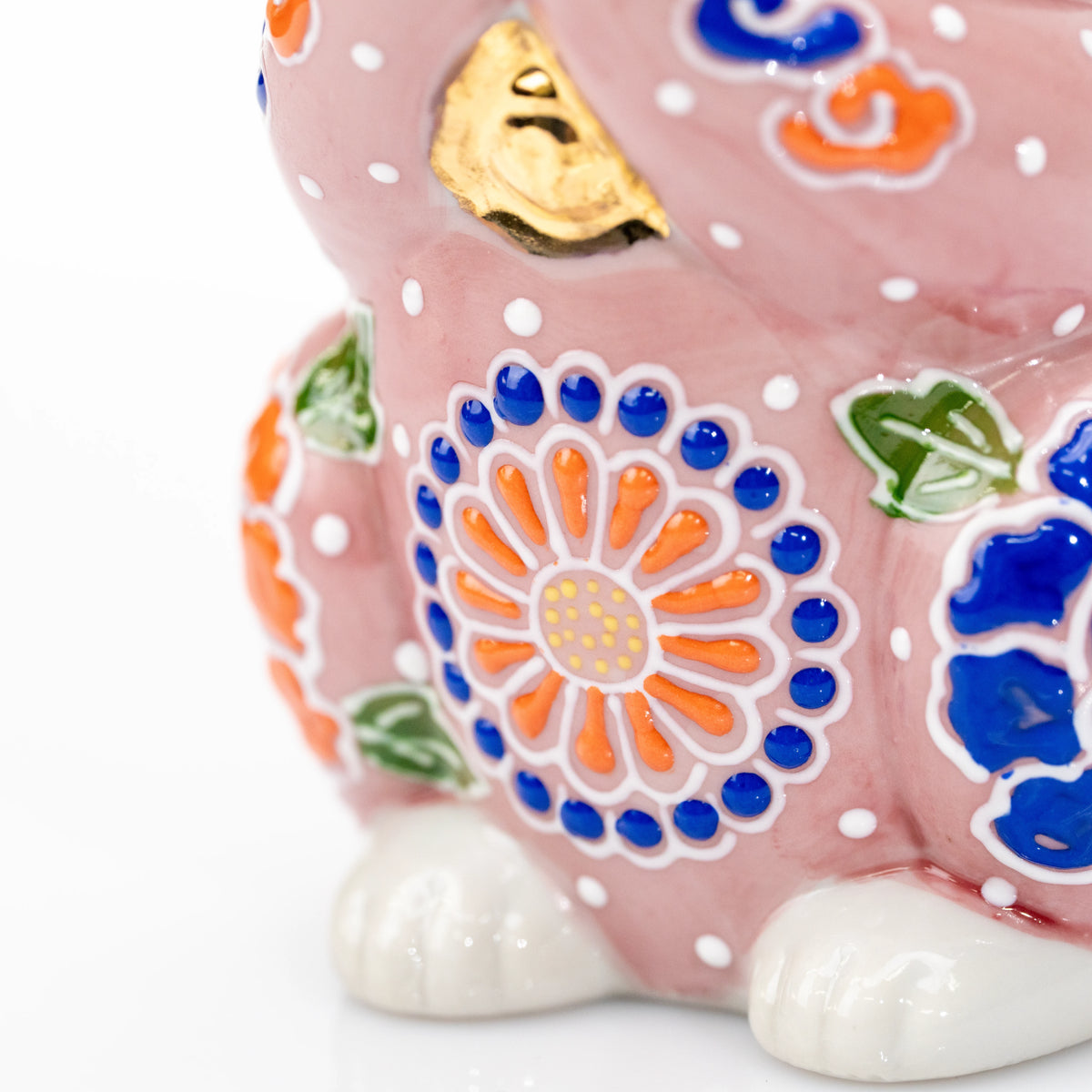Gold bell and orange flower on the front of the pink cat.
